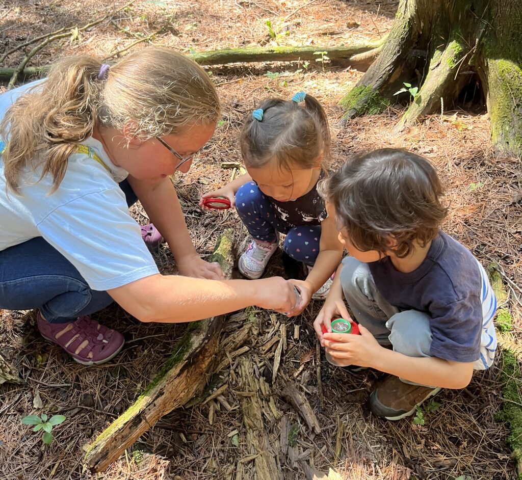 Mom and two young children look under a log